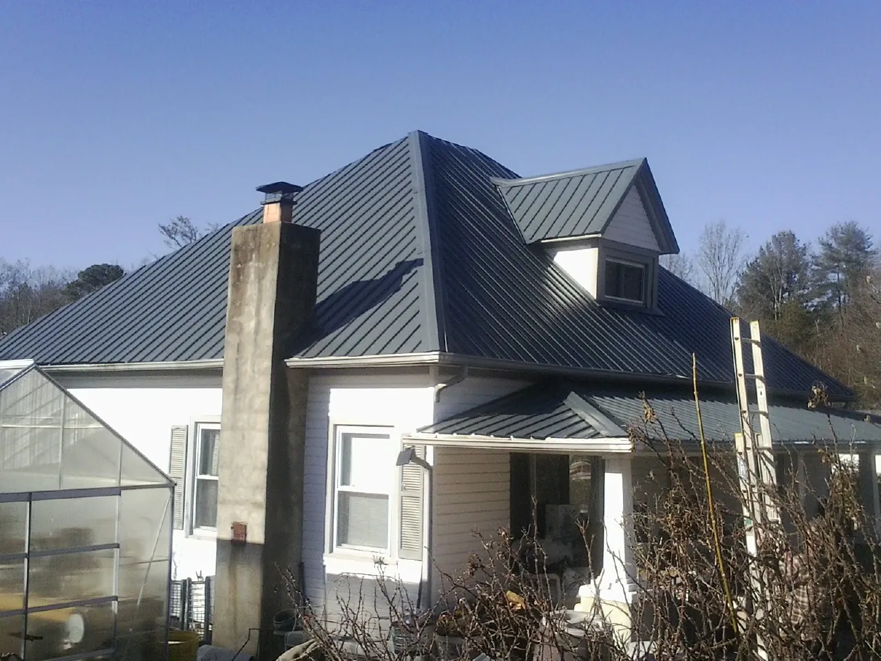 Dark blue standing seam metal roof on a white farmhouse with dormer — Slate & Tile Roof Repair by Roofing Brothers in Bowers