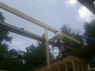 Carpenter setting a ridge beam over a new addition frame — Ice Dam Removal by Roofing Brothers in Bowers
