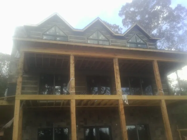Dormers and porch framing on a large log home under construction — Roof Coating work by our crew in Bowers