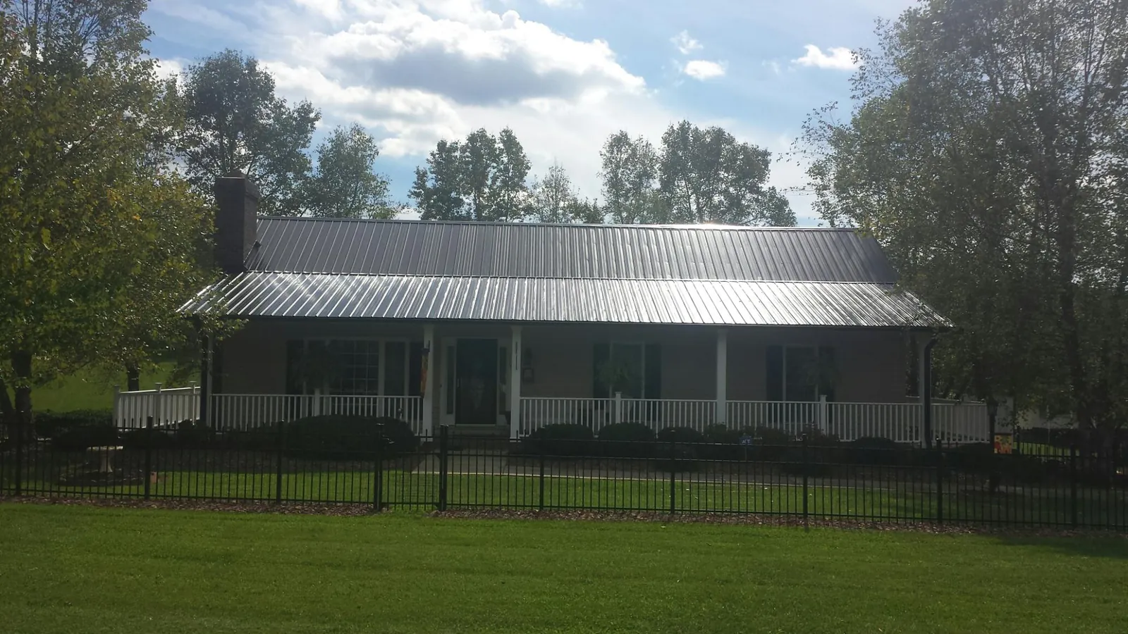 Gray metal roof on a brick ranch with a full width front porch — Gutter Guard Installation work by our crew in Bowers