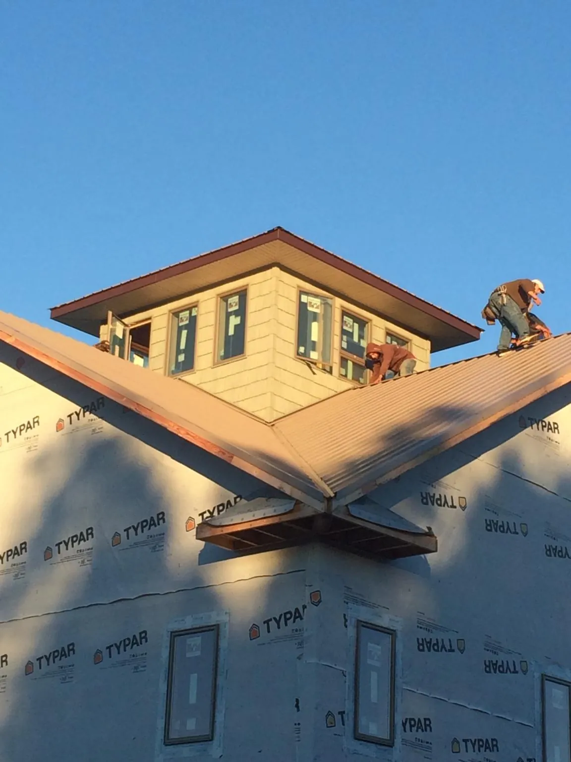 Roofers working around a rooftop cupola on a new metal roof at sunset — Roof Waterproofing in Bowers by Roofing Brothers